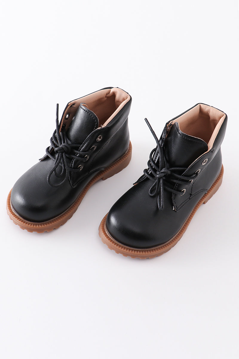 A pair of black faux leather booties with lace-up fronts and brown soles.