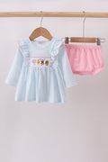 Children's dress with ruffled sleeves and pink shorts on hangers against a light background